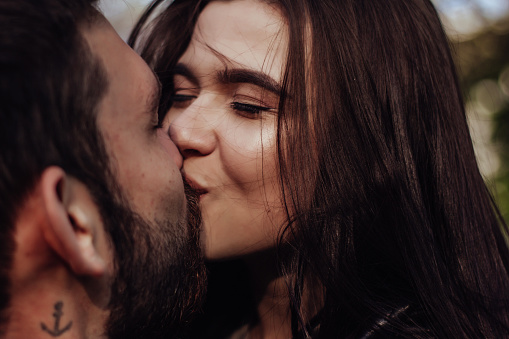 Head shot of young affectionate romantic couple in love. Close up portrait of attractive brunette girl and guy with eyes closed, close to each other. Concept of first kiss, tenderness and amorousness