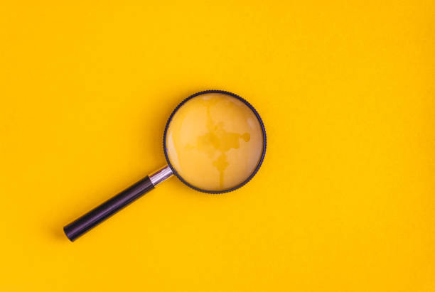 Magnifier lies on yellow and blue background. View from above. Flat lay. Copy space stock photo