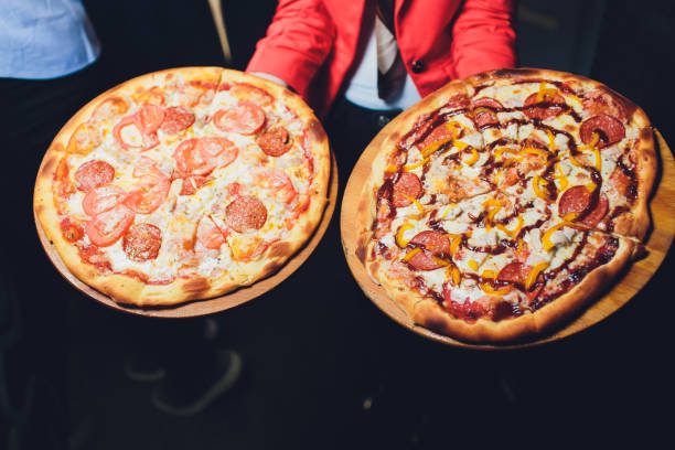 kelner niosący dwa różne talerze ze smaczną pizzą. zdjęcie z dwiema pizzą. pizza z grzybami i pizza z salami. włoskie jedzenie. włoska restauracja. - carton horizontal portion part of zdjęcia i obrazy z banku zdjęć