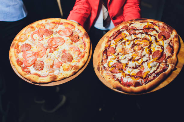 empregado de mesa que carreg duas placas diferentes com uma pizza saboroso. foto com duas pizzas. pizza com cogumelos e pizza com salame. comida italiana. restaurante italiano. - carton horizontal portion part of - fotografias e filmes do acervo