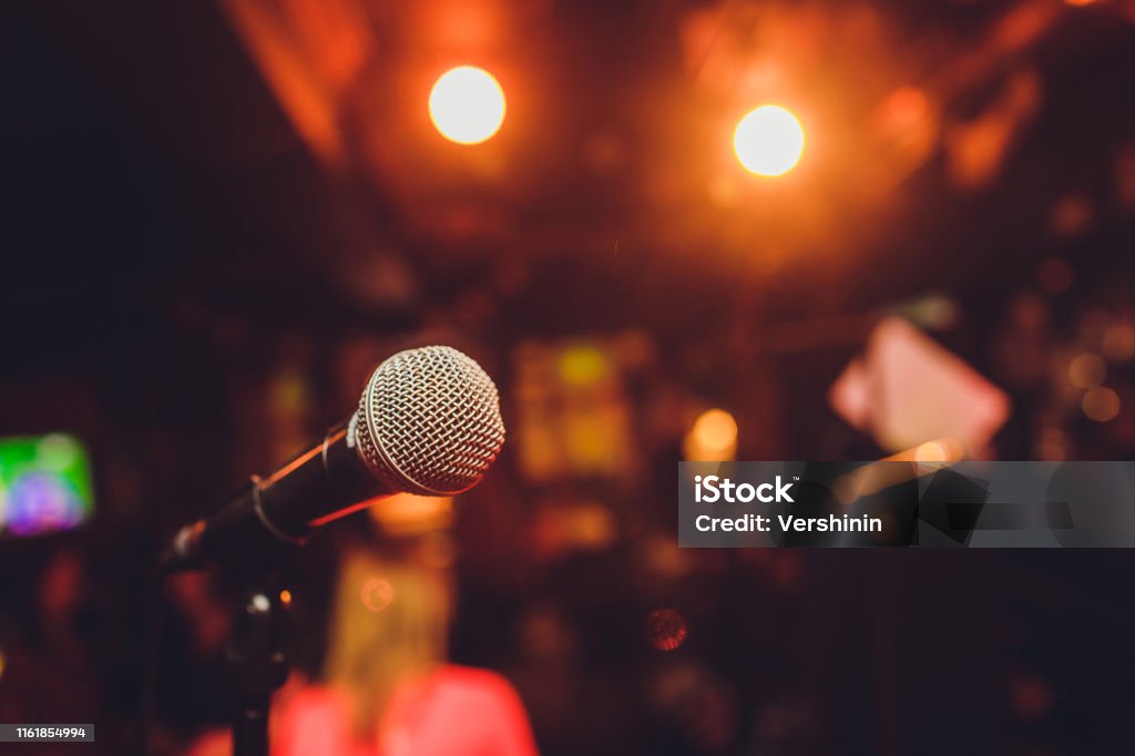 Microphone on stage against a background of auditorium. Microphone on stage against a background of auditorium Comedian Stock Photo