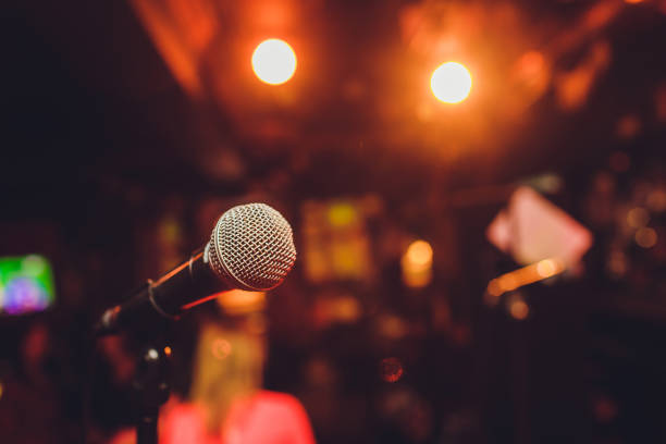 Microphone on stage against a background of auditorium. Microphone on stage against a background of auditorium comedian stock pictures, royalty-free photos & images