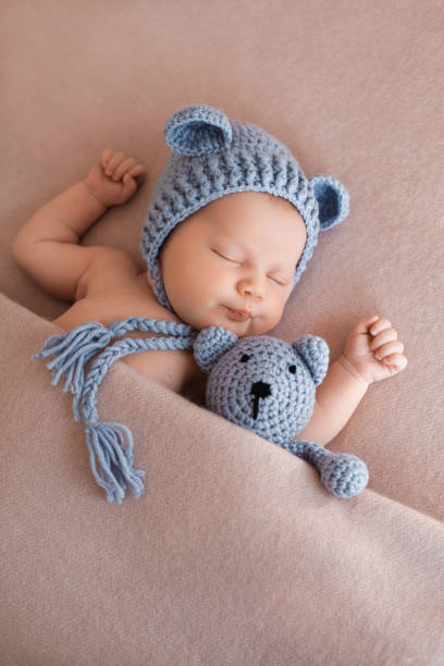 Cute newborn baby girl sleeping with a teddy bear. Portrait of cute newborn baby girl sleeping with knitted teddy bear under pink blanket. Vertical Image. baby boys photos stock pictures, royalty-free photos & images