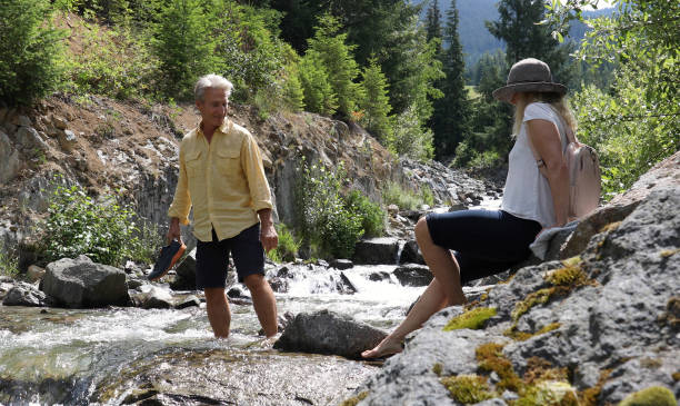 istock Mature couple cross mountain stream in forest 1161861369
