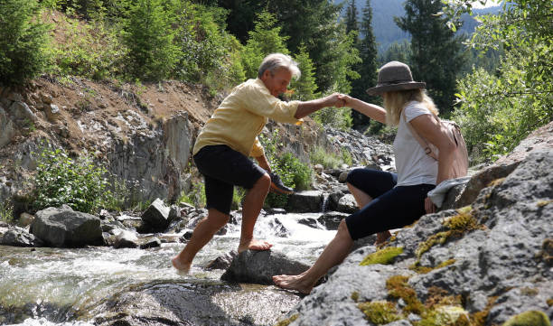 istock Mature couple cross mountain stream in forest 1161861421