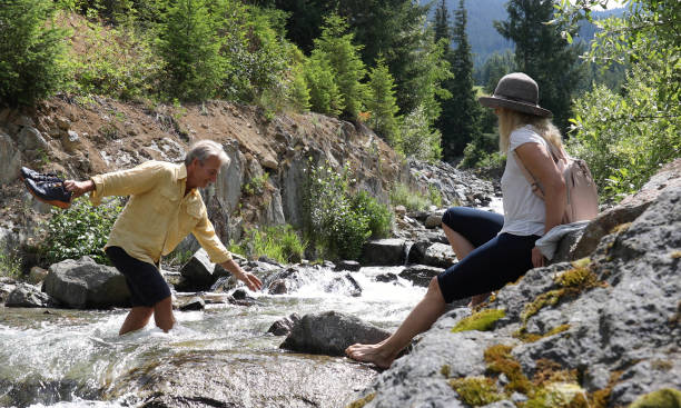 istock Mature couple cross mountain stream in forest 1161861440