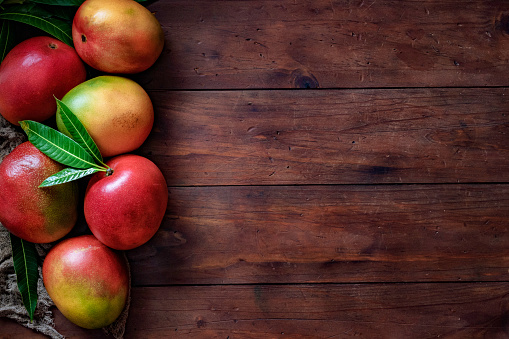 Healthy eating themes. Tropical Fruits: Mangos making a frame with copy space on a wooden table in rustic kitchen