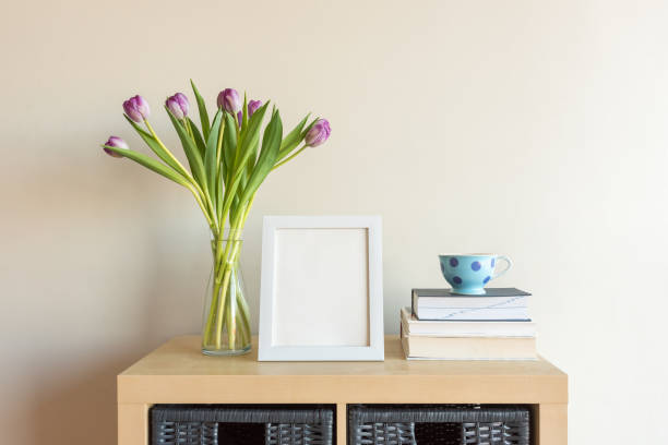 istock Blank frame, purple tulips, cup and books on cabinet 1161890115