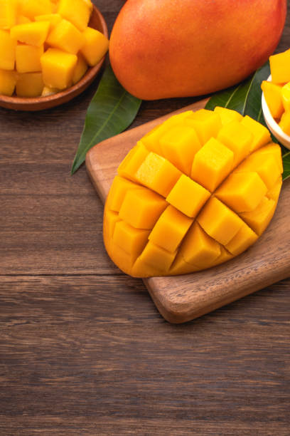 istock Fresh Mango - Juicy chopped mango cubes on wooden cutting board and rustic timber background. Tropical summer concept. Close up, macro, copy space. 1161891134