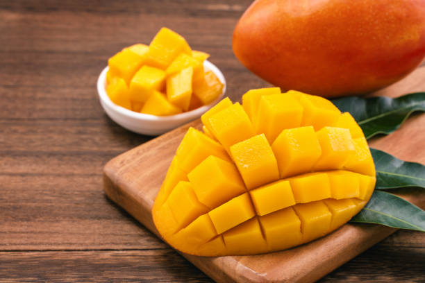 istock Fresh Mango - Juicy chopped mango cubes on wooden cutting board and rustic timber background. Tropical summer concept. Close up, macro, copy space. 1161891196
