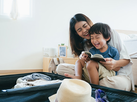 Young asian woman and little baby boy preparing for road trip at home.