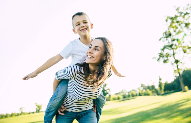 istock Happy beautiful young mother is playing with her little son while he is riding on her back and shouting for joy. 1161894402