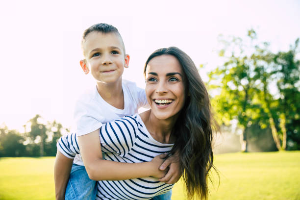 istock Happy beautiful young mother is playing with her little son while he is riding on her back and shouting for joy. 1161894428