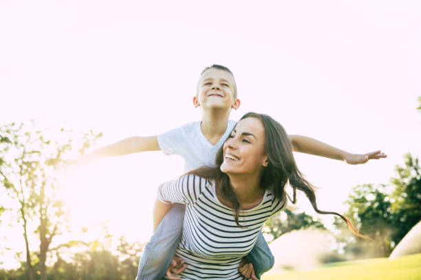 istock Happy beautiful young mother is playing with her little son while he is riding on her back and shouting for joy. 1161894476