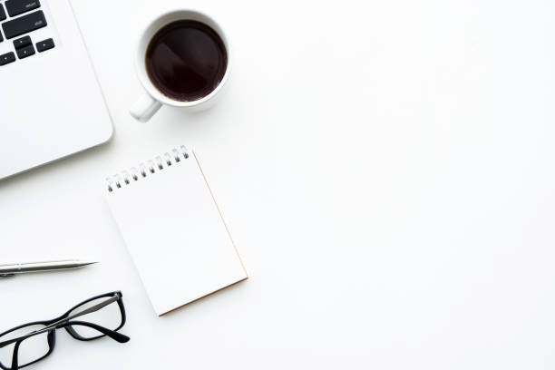 istock White office desk table with small blank notebook, laptop computer, cup of coffee and supplies. Top view with copy space, flat lay. 1161900403