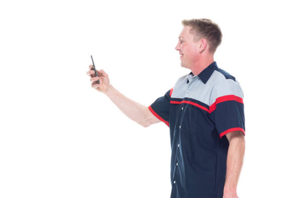 istock Young handsome male mechanic standing on white background - texting on smart phone 1161903725