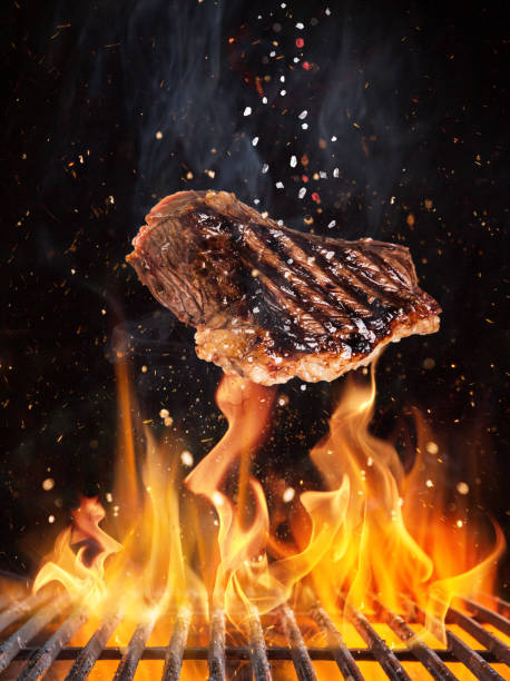 istock Tasty beef steaks flying above cast iron grate with fire flames. 1161909049