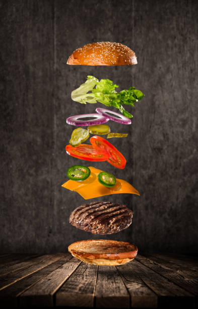 Tasty cheeseburger with flying ingredients on dark background