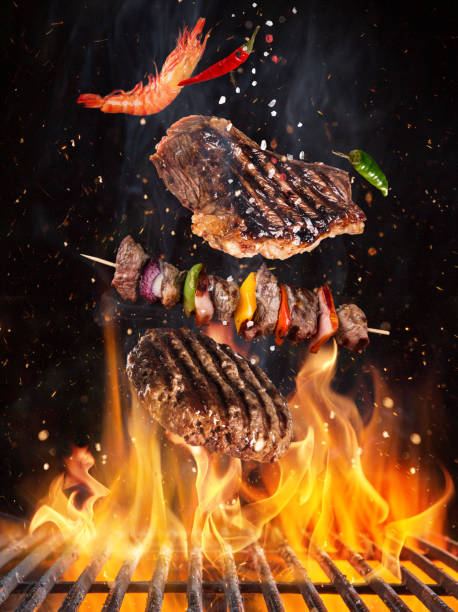 istock Tasty beef steaks and skewers flying above cast iron grate with fire flames. 1161914821