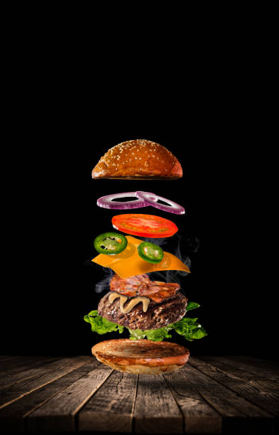 istock Tasty hamburger with flying ingredients on dark background 1161914846