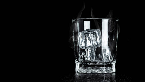 istock Empty glass with ice cube on dark background with cooling smoke and blank space. Ice blocks for beverage. 1161920806