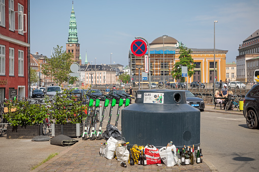 Copenhagen, Denmark - June 26, 2019: Filled bottle container for recycling in central Copenhagen with a view to Thorvaldsens Museum and the tower of Nicolaj Church