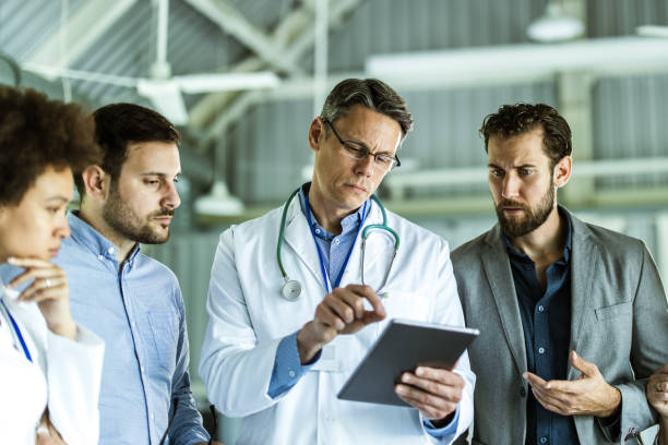 istock Two businessmen and doctors working on touchpad in a hospital. 1161924885