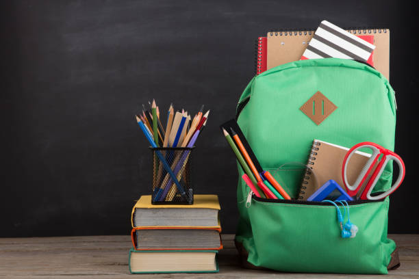 istock Education concept - school backpack with books and other supplies, blackboard background 1161926262