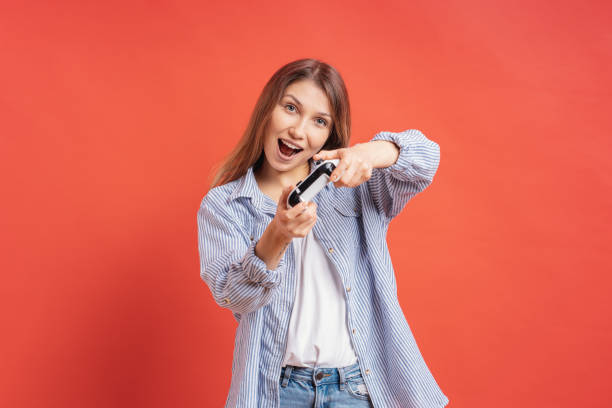 Excited casual young woman playing video games having fun on red background stock photo