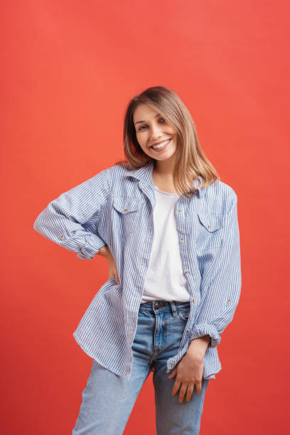 istock Pretty female model posing with a smiling face expression on red background 1161932429