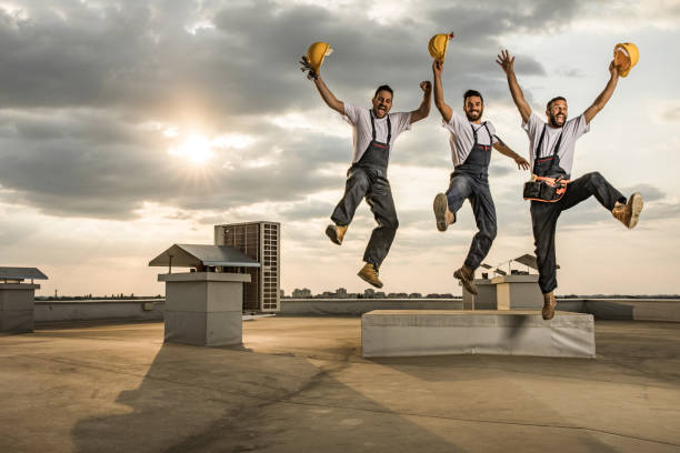 We have succeeded to finish the building! Group of happy construction workers jumping on the roof because they have successfully build a building. repairperson occupation stock pictures, royalty-free photos & images