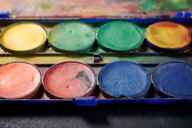 Box of watercolors and brushes on a table.