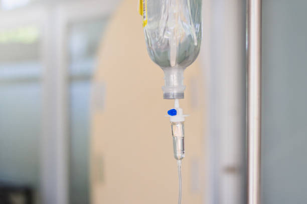 istock Intravenous therapy iv infusion set and bottle on a pole. Liquid saline is slowly dripping drops of drugs, medicine or antibiotic therapy and surgery recovery in a hospital or clinic 1161941359