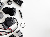 top view of work space photographer with digital camera, flash, cleaning kit, memory card, tripod and camera accessory on white table background