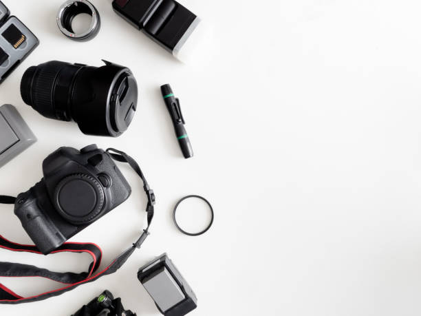 top view of work space photographer with digital camera, flash, cleaning kit, memory card, tripod and camera accessory on white table background stock photo