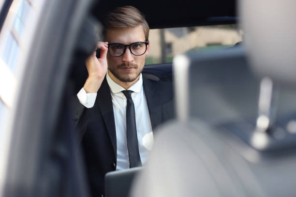 istock Thoughtful confident businessman keeping hand on glasses while sitting in the luxe car. 1161948013