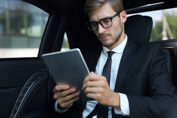 istock Thoughtful young businessman sitting in the luxe car and using his tablet. 1161948049