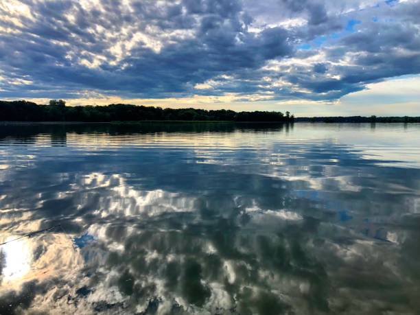 istock Sunrise on smooth lake with reflection of sun and clouds on water 1161949378