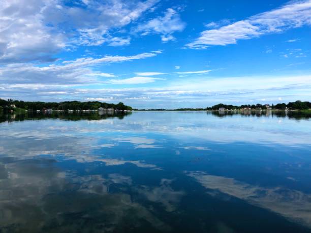 Sunrise on smooth lake with reflection of sun and clouds on water