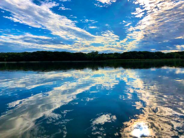 istock Sunrise on smooth lake with reflection of sun and clouds on water 1161949381