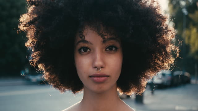 Portrait of a young woman with afro hair in the city at sunset