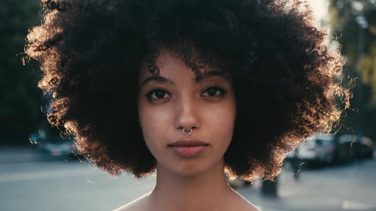 Portrait of a young woman with afro hair in the city at sunset