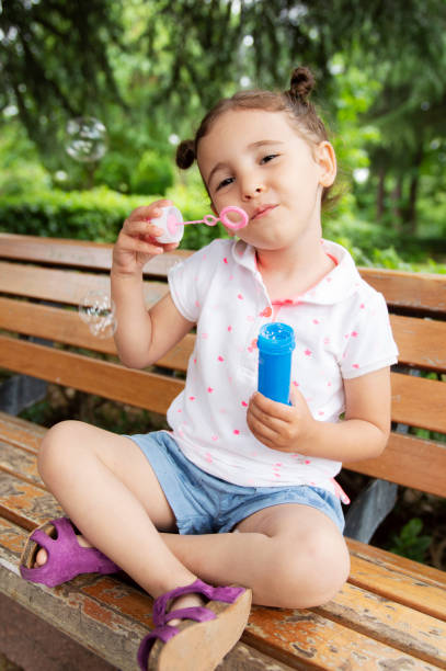 istock Little girl blowing soap bubbles 1161951894