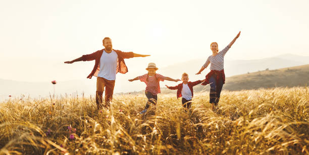 famille heureuse : mère, père, fils d'enfants et descendant sur le coucher du soleil - son photos et images de collection