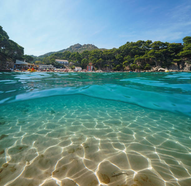 Spain Costa Brava beach in summer and sandy seabed underwater, split view half above and below water surface, Aiguablava, Begur, Catalonia, Mediterranean sea