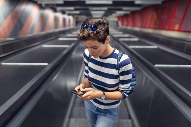 A woman using her phone on an escalator