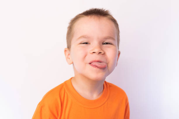 istock A little boy shows tongue with a cheerful expression on his face, on a light background 1161958709