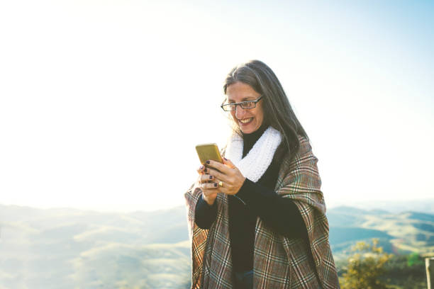 istock Woman using cell phone on top of the mountains 1161963061