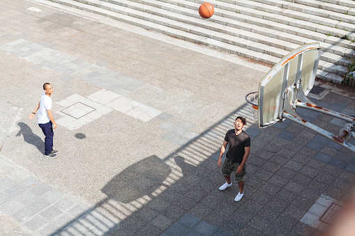 Two friends are playing basketball in the city.