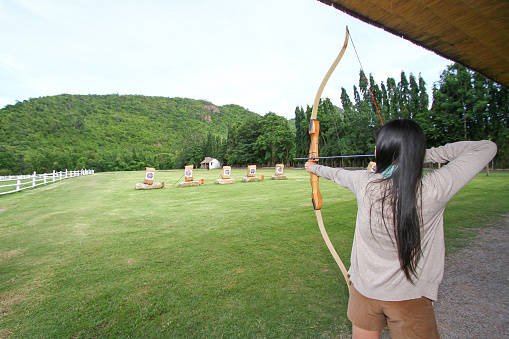 Women standing on the grass are shooting arrows